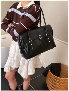 Gros plan du sac cabas rétro noir avec boucle argentée et texture cuir sur un mannequin