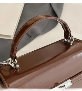 Close-up of wide brown leather handbag handle with polished silver hardware details