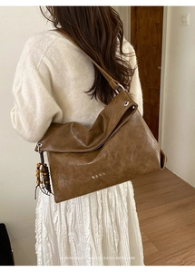 Detailed close-up of brown soft leather hobo bag featuring retro wooden bead tassels