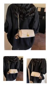 Close-up of cream leather crossbody bag with gold buckle and brown plush monster charm