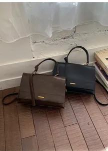 Detail of vintage leather handbags in brown and black with gold hardware on wooden floor