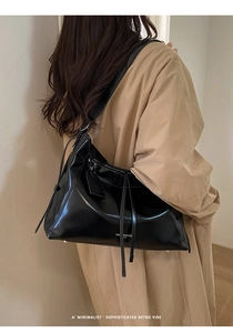 Detail of glossy black large tote bag with chain strap in a minimalist hobo style