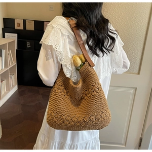 Detail of hand-crocheted floral texture on hobo bag with leather strap and metal buckle