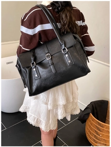 Détail d'un grand cabas vintage en cuir noir avec boucles argentées et rivets à l'épaule