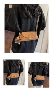 Detail view of tan leather crossbody bag featuring gold U-shaped lock and plush charm