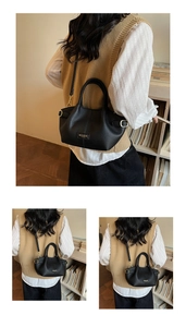 Détail du sac seau en cuir noir montrant les sangles réglables et le logo métallique