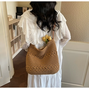 Detailed close-up of brown woven hobo bag featuring 3D floral crochet patterns and leather strap