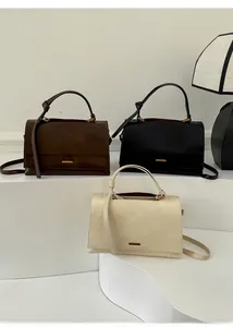Close-up of three elegant tote bags in brown, black and beige with gold metal plaques