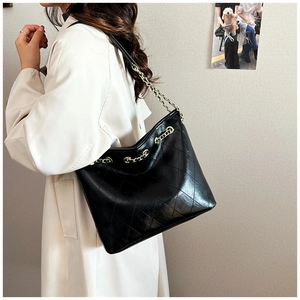 Chic black quilted tote bag with gold chain strap worn with a white trench coat