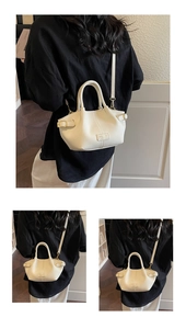 Détail du sac seau en cuir blanc cassé montrant sa texture grainée et ses boucles dorées