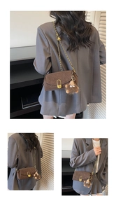 Detail of brown suede crossbody bag featuring gold chain and plush monster charm
