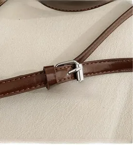 Detailed close-up of dark brown leather shoulder strap with silver metal buckle and stitching