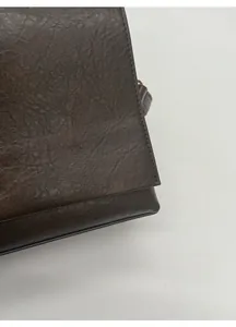 Close-up of deep brown PU leather texture and neat stitching on a minimalist shoulder bag