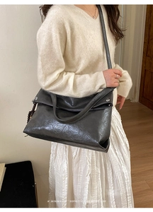 Chic black shoulder bag with oil wax texture shown on model in a minimalist setting