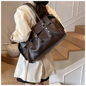 Gros plan détaillé du sac cabas en cuir marron foncé avec texture vintage et rivets