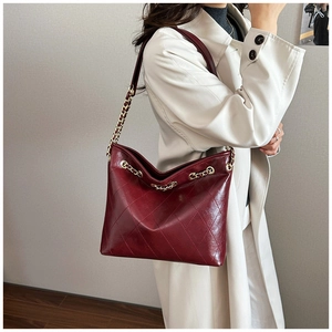 Detail of wine red quilted tote bag with glossy finish and elegant gold chain strap