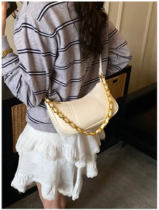 Detail of a creamy white hobo bag with a gold chain strap and smooth leather texture