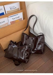 Detail of glossy dark brown leather tote bags with brand logo in a cozy home setting