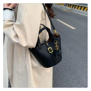 Detail of black pebbled leather bucket bag with gold buckle and leather horse charm