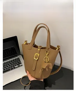 Detailed view of brown lychee texture bucket bag with gold buckle and elephant charm