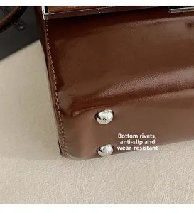 Detail view of silver metal rivets on dark brown leather bag bottom for wear resistance