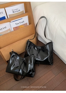 Detailed comparison of two glossy black tote bags in large and small sizes on wooden floor