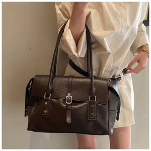 Détail du sac cabas en cuir marron foncé avec boucle vintage et texture brillante
