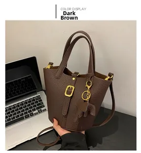 Detail of dark brown lychee leather bucket bag with golden buckle and elephant charm