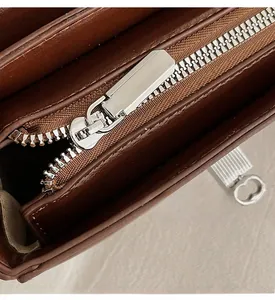 Close-up of smooth silver zipper and stitching on the dark brown leather handbag