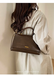 Detailed view of vintage dark brown tote with elegant gold metal logo on a smooth finish