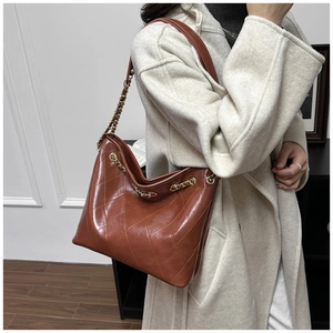 Brown quilted tote bag showing large diamond stitching and metal chain shoulder strap detail