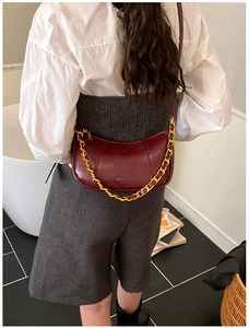 Close-up of wine red oil wax leather crescent bag with decorative gold chain detail