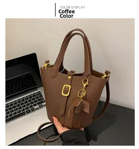 Detailed close-up of brown litchi pattern bucket bag with cute elephant charm and gold buckle