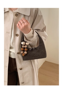 Close-up of a vintage brown leather crescent bag with a decorative polka dot bow charm