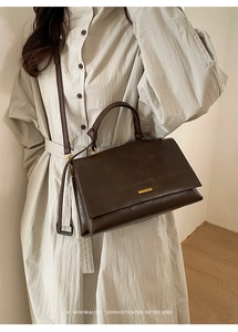 Close-up of dark brown retro leather tote bag with gold hardware and brand logo plate
