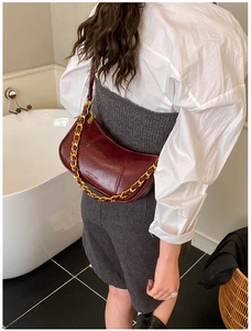 Detail of dark red dumpling bag with polished wax leather and gold chain strap decoration