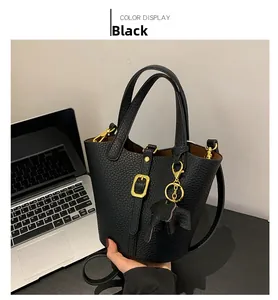 Detail of black lychee grain leather bucket bag with gold hardware and shoulder strap