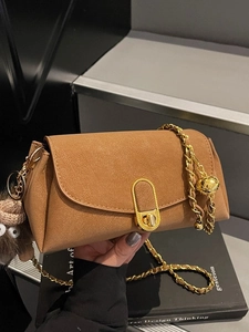 Brown square crossbody bag with gold chain strap and plush pendant in a 45-degree view