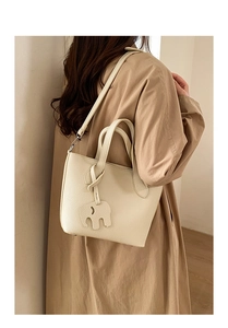 Détail du sac seau crème texturé avec pendentif éléphant et bandoulière amovible