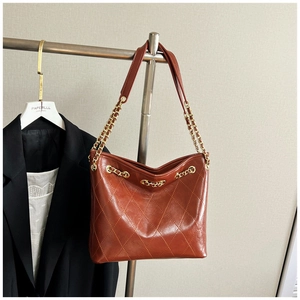 Detail of caramel brown quilted tote bag with gold chain strap and vintage wax leather texture