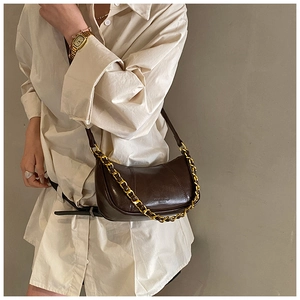 Detail of dark brown vintage crescent bag with gold chain and pleated wax leather texture