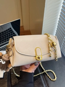 Cream square shoulder bag with gold chain strap and plush monster pendant