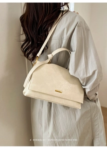 Detail view of cream white shoulder bag with gold hardware and removable crossbody strap