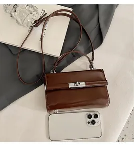 Detail view of a vintage dark brown square handbag with silver rotating lock and shoulder strap