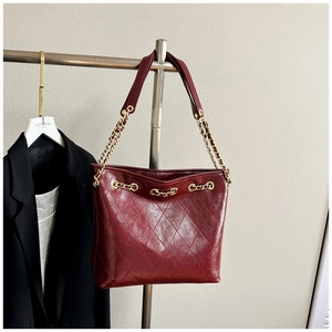 Close-up of quilted wine red leather tote bag with elegant gold chain shoulder strap