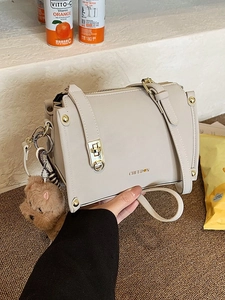 Elegant cream Boston handbag with gold hardware and a cute plush bear charm