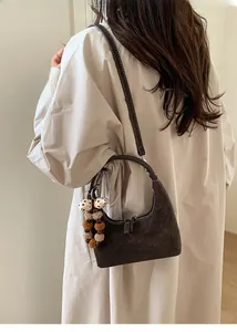 Detail of dark brown matte hobo bag with plush charm on a model wearing a trench coat
