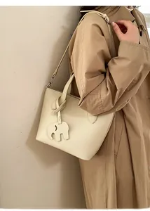 Gros plan sur un sac cabas en cuir grainé blanc cassé avec breloque éléphant