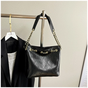 Detail of black quilted leather tote with gold chain strap and elegant metal hardware