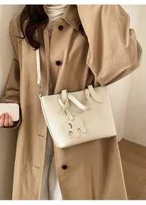 Sac seau chic en cuir grainé crème avec breloque éléphant porté par un mannequin